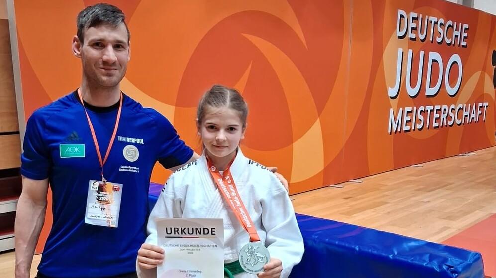 Alexander Lenkt steht neben Greta Emmerling die eine Urkunde &uuml;ber den zweiten Platz sowie eine Medaille hochh&auml;lt.