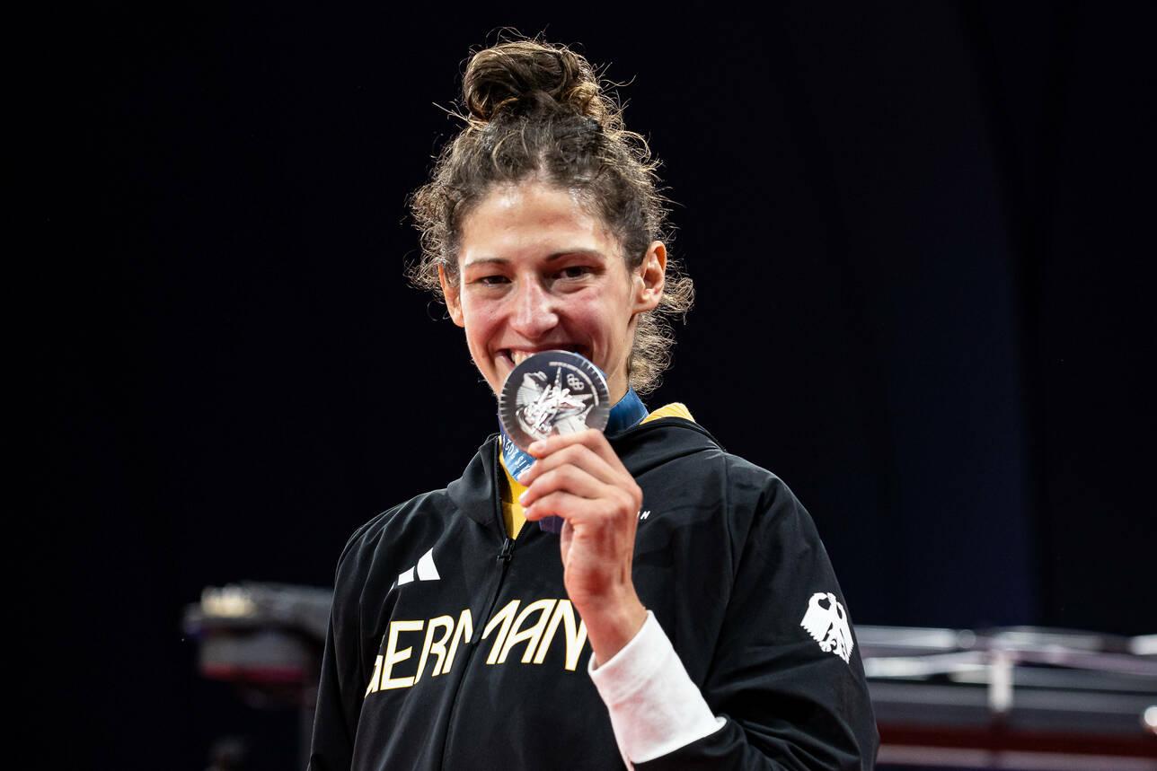 Miriam Butkereit Silber Sportlerin in schwarzer Jacke hält stolz eine Silbermedaille vor ihrem Gesicht und lächelt auf einer Bühne.