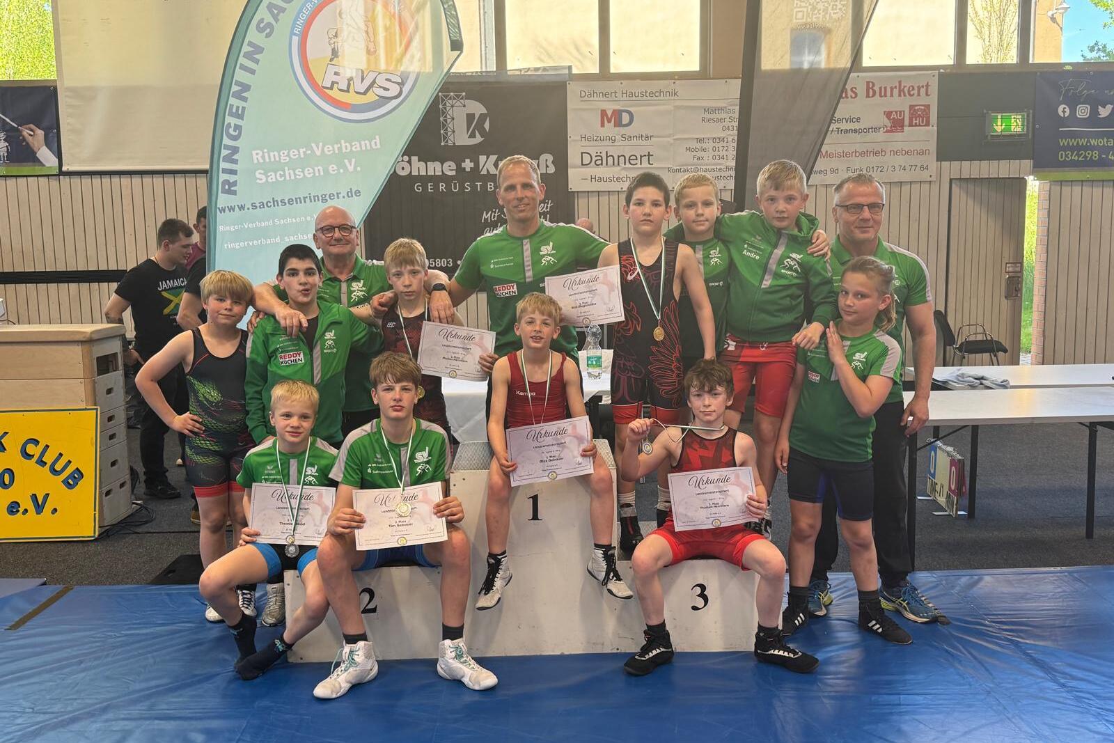 Die Sportler und Trainer aus der Abteilung Ringen posierern f&uuml;r ein Mannschaftsfoto mit Urkunden und Medaillen.
