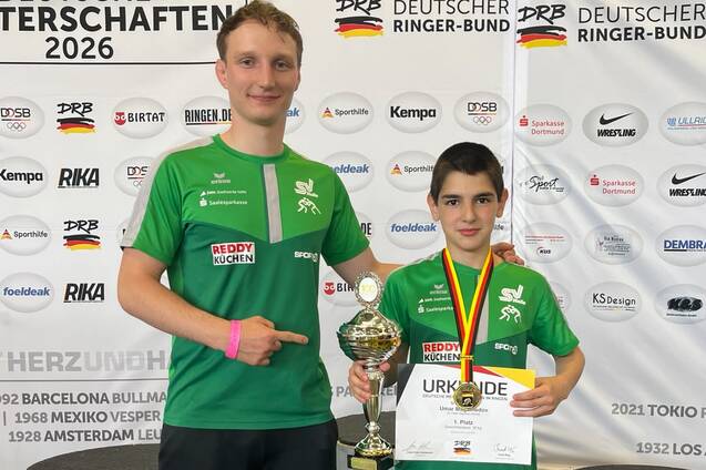 Umar Magamedov und sein Trainer zeigen ihren Pokal und Medaille.