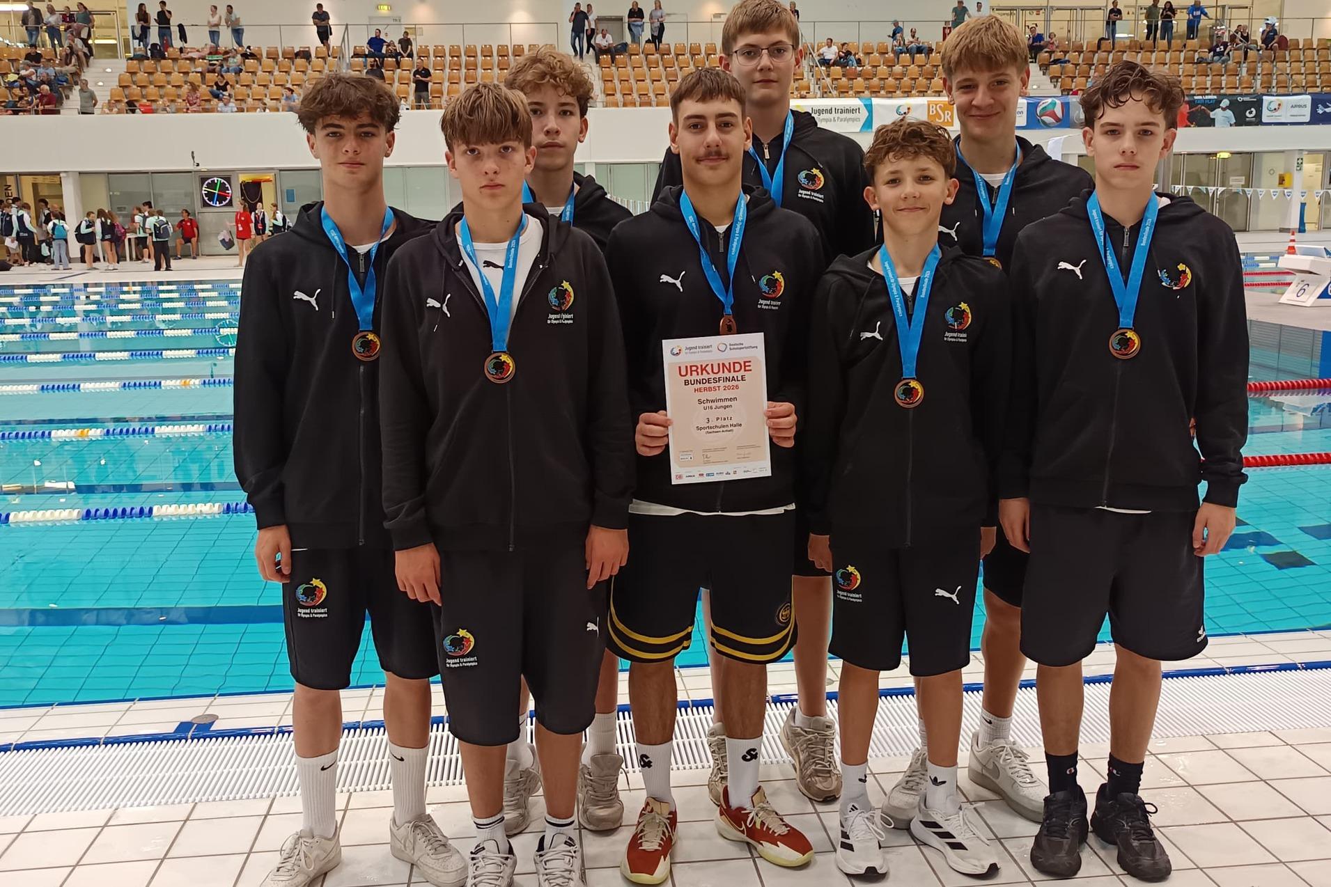 JtfO-2026-Platz-3-mit-Medaille Die Teilnehmer aus der Abteilung Schwimmen im Gruppenfoto über den dritten Platz bei Jugend trainiert für Olympia 2026.
