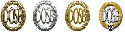 Vier Medaillen in Gold, Silber und Bronze mit dem Schriftzug „DOSB“ in einer ovalen Form und eine Jubiläumsmedaille.