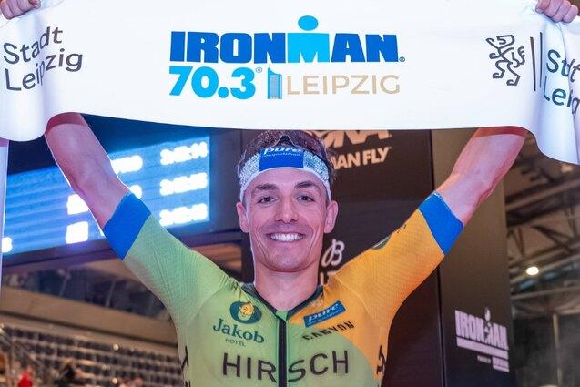 Willy Hirsch gewinnt den Iron Man in Leipzig und h&auml;lt ein Banner hoch.
