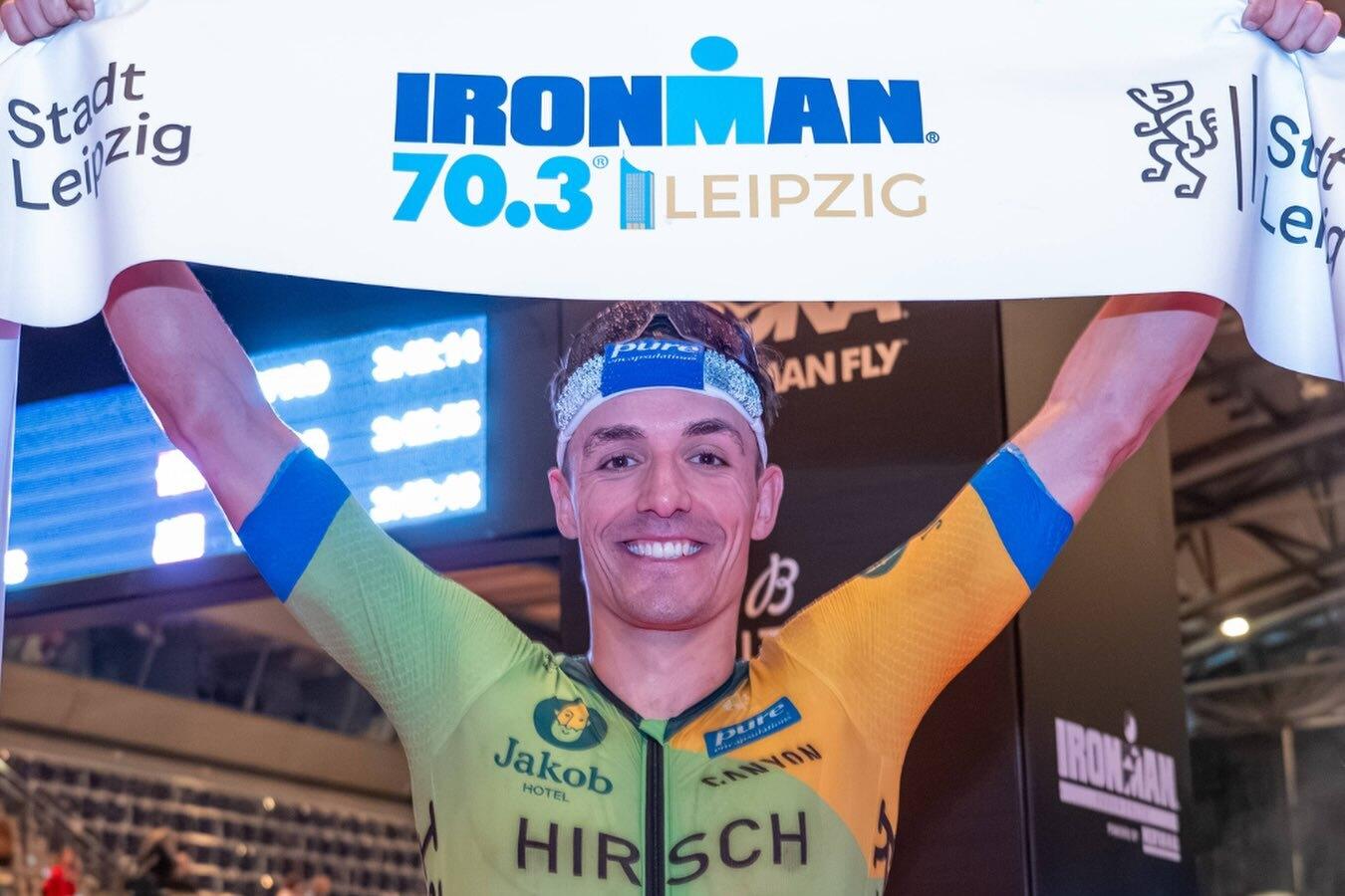 Willy Hirsch gewinnt den Iron Man in Leipzig und h&auml;lt ein Banner hoch.