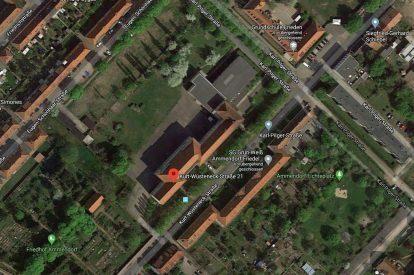 Luftaufnahme eines Stadtgebiets mit Wohngebäuden und Straßen, umgeben von Bäumen und Grünflächen.