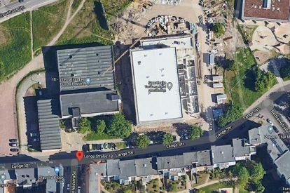 Luftaufnahme eines Baustellenbereichs mit mehreren Gebäuden und Straßen in der Umgebung.